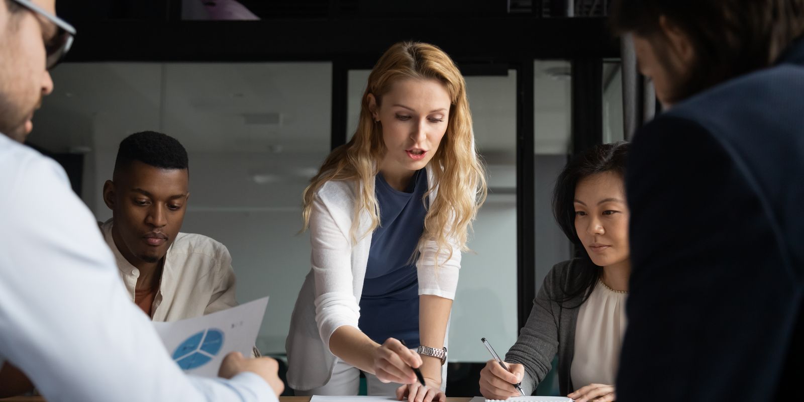 A team leader walking colleagues through documents around a meeting table